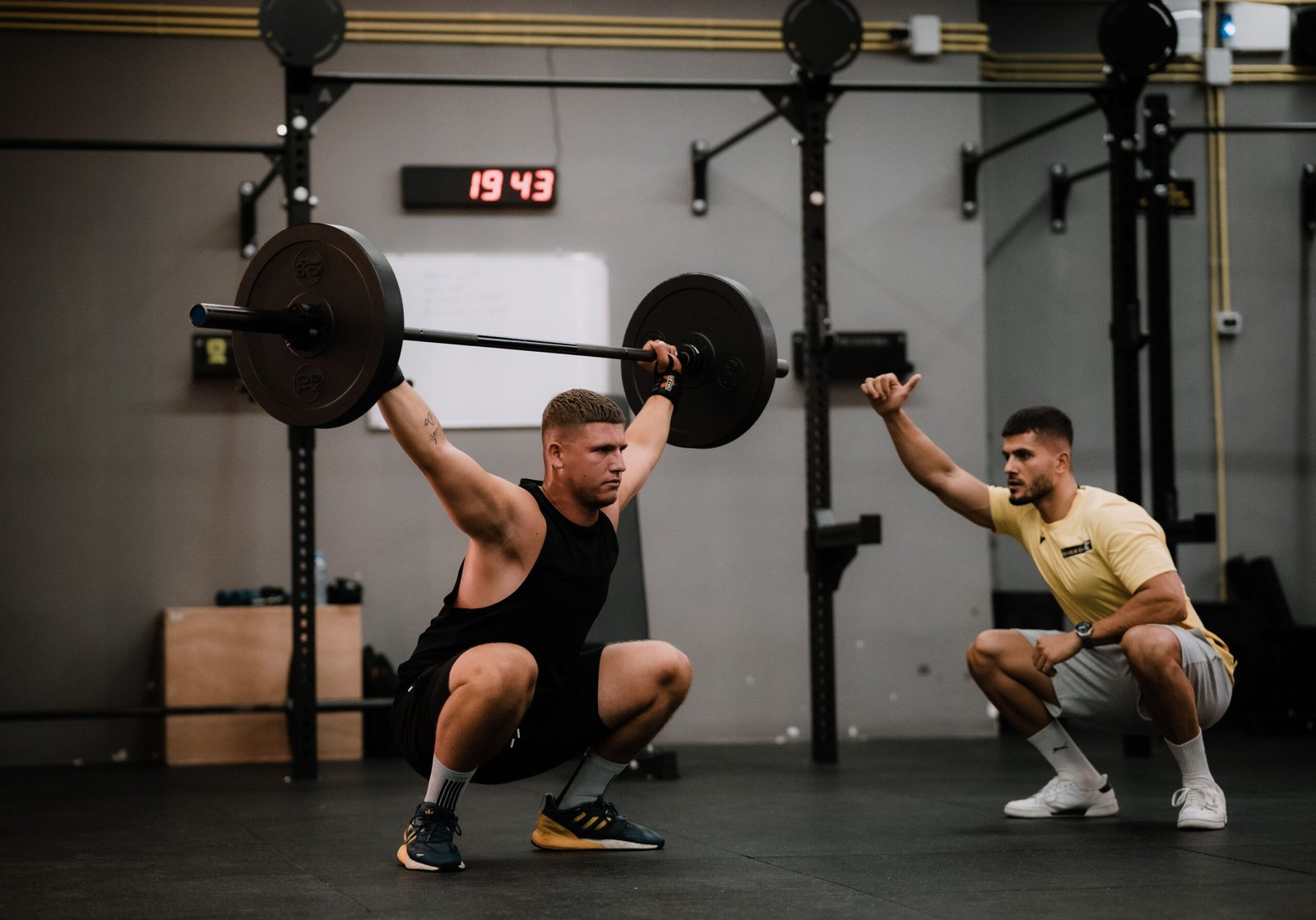 Coach teaching compound exercises to build strength with proper movement and technique.