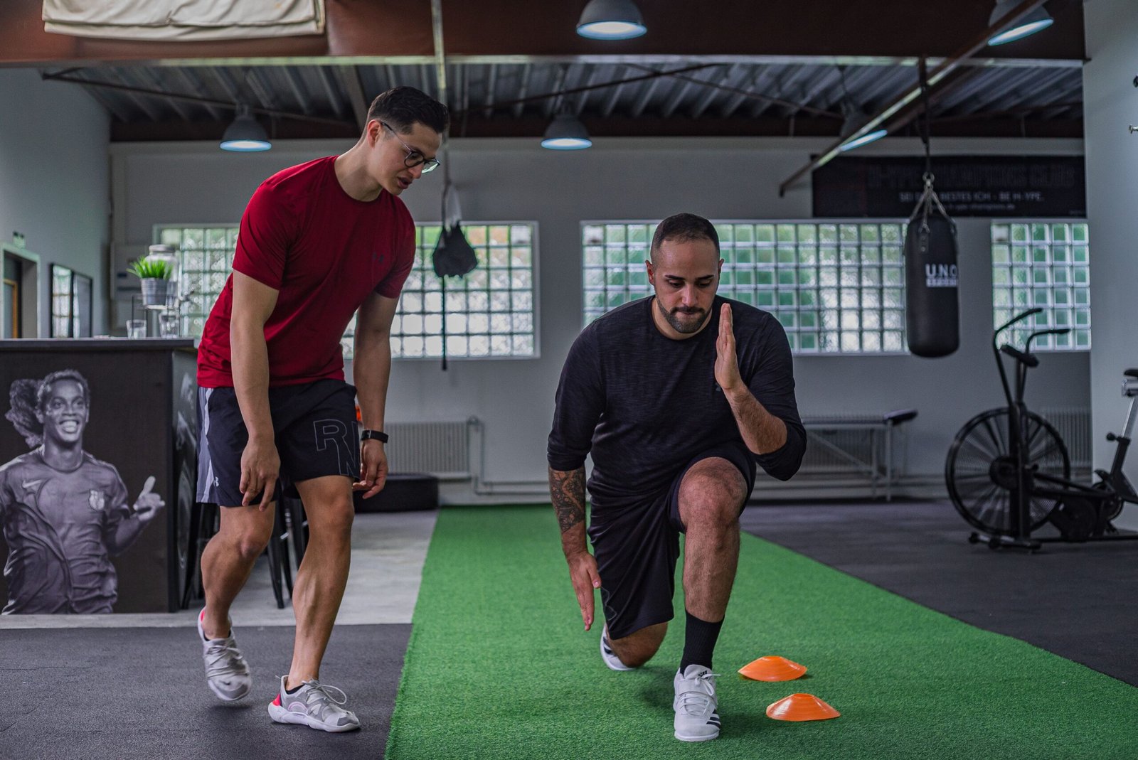 Coach teaching progressive overload through proper strength training technique.