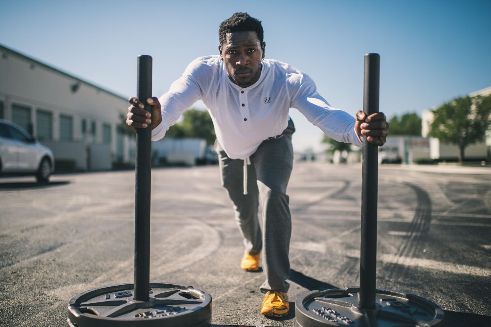 Man performing power training by pushing a weighted sled to develop explosive strength, speed, and full-body force.